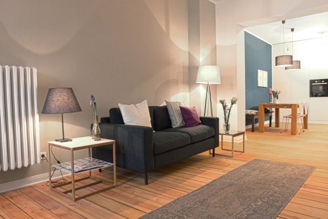 Eine schwarze Couch steht in einer Altbauwohnung mit neuen Dielen